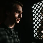 Man confessing in a dark church confessional, evoking themes of shame, judgment, and secrecy